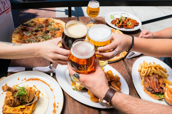 People cheersing beer over bar snacks