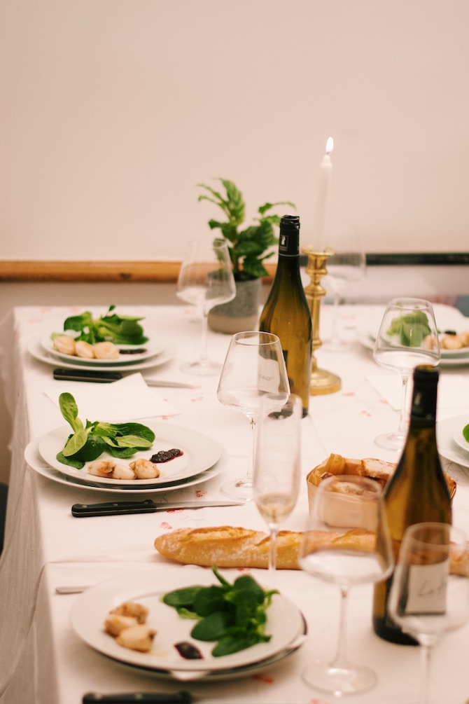 A dining table set with plates, food, and wine