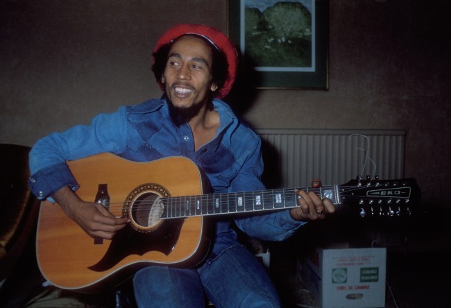 Bob Marley playing a guitar in a hotel room in London, UK.