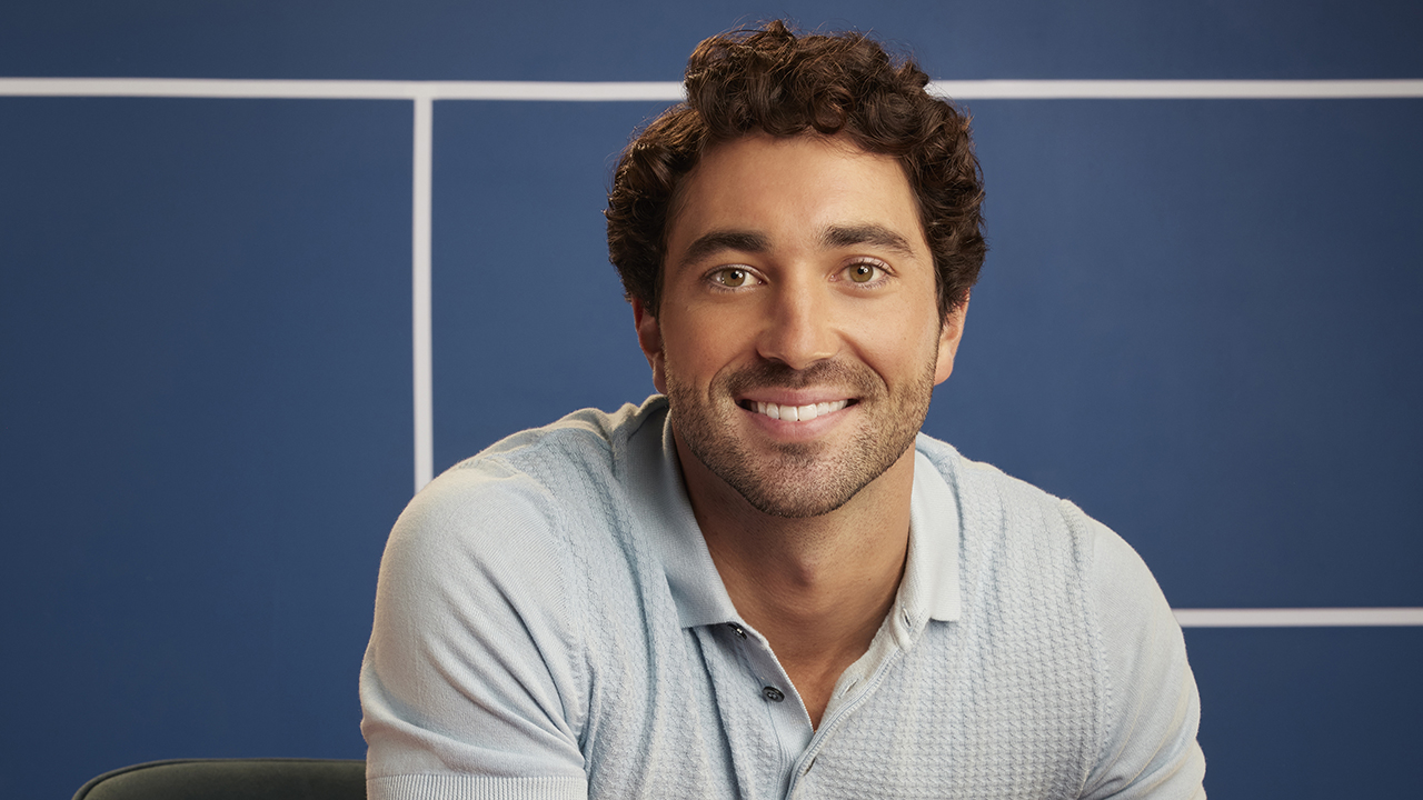 “The Bachelor” stars Joey Graziadei, a white man with brown hair and bear wearing a blue polo