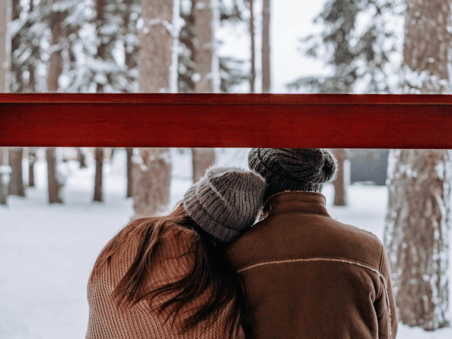 A young couple share a special moment in the snow. One lays her head on the others shoulder.