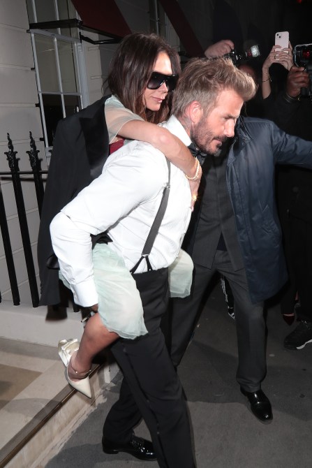 Victoria Beckham on David Beckham's back as she leaves her birthday party.