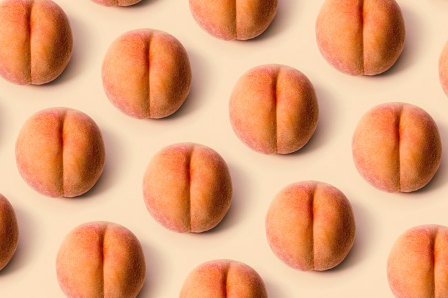 A detailed image of a freshly picked ripe peach.  Photographed on a peach colored background. Representation of anal sex.