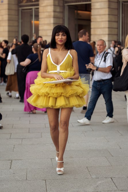 Woman wears short mustard yellow ruffled tule dress outside Giambattista Valli