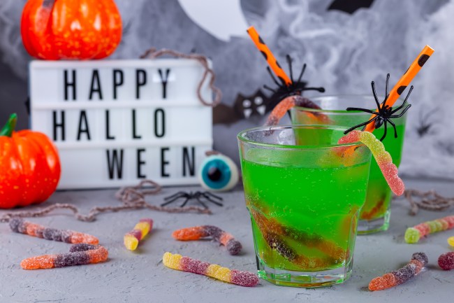 Spooky Halloween cocktail with green bubble drink and candy worms