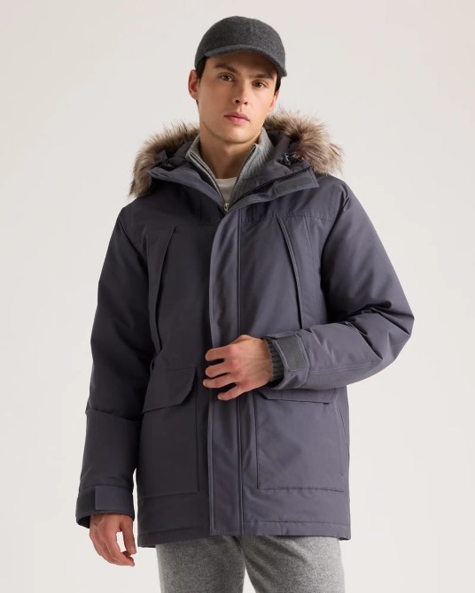 A model wearing the Quince Responsible Down Hooded Parka in Carbon Grey