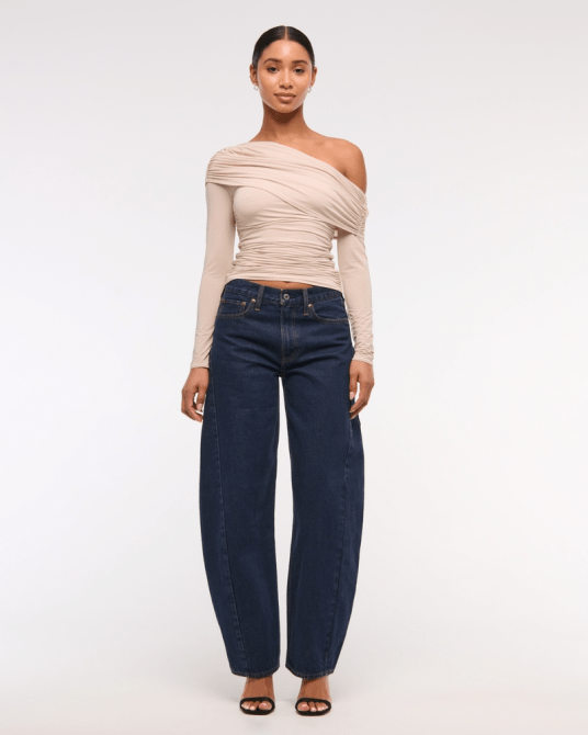 A model wearing Abercrombie & Fitch's Mid Rise Barrel Jean in a dark wash