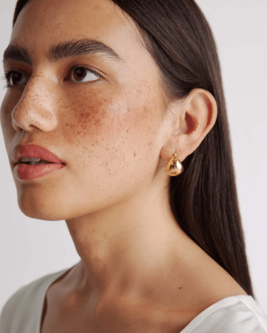 A model wearing Quince's Globe Boho Hoops in gold