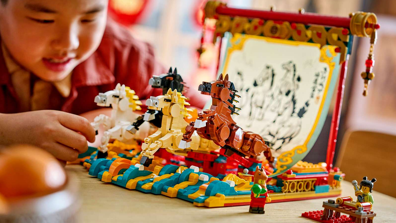 A little boy playing with a LEGO Lunar New Year Year of the Horse galloping horse set