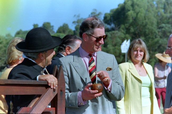 Prince Charles visits Las Brujas Farm in Uruguay where a gaucho encourages him to try a drink of 'Mate', a traditional South American tea which he found very amusing, 12 March 1999. Watching on is Prince Charles's press secretary, Sandy Henney.